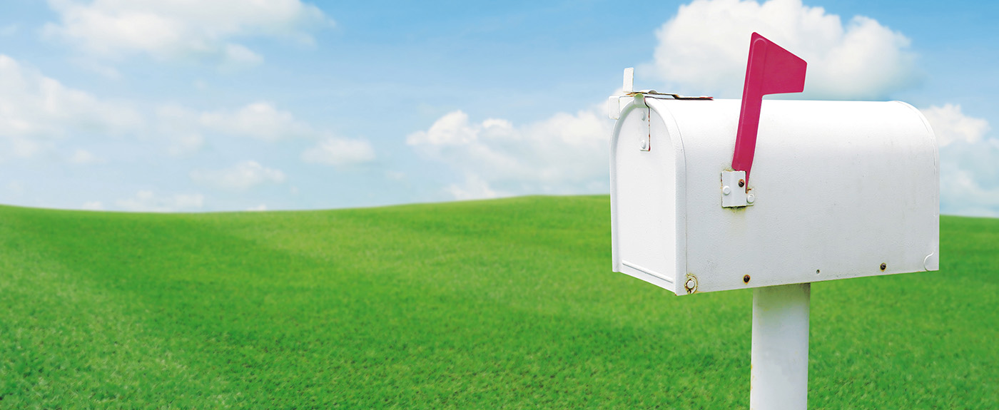 Vintage white post mailbox with blured outdoor green lawn grass and blue sky